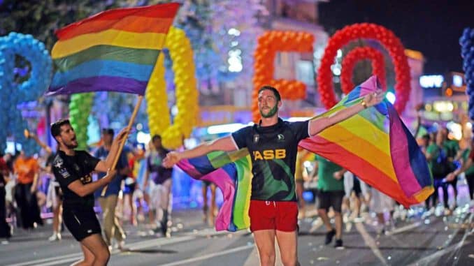 Auckland Pride, junger Mann schwenkt die Regenbogenflagge